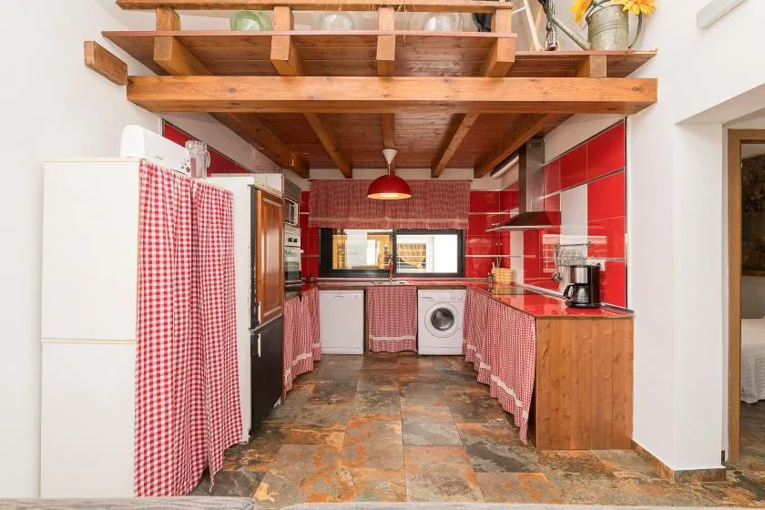 A kitchen with red tiled walls, wooden counters, and a washing machine.