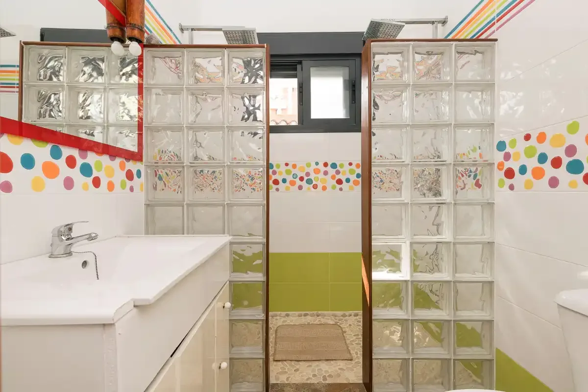 A colorful bathroom with a white sink and glass block partitions.