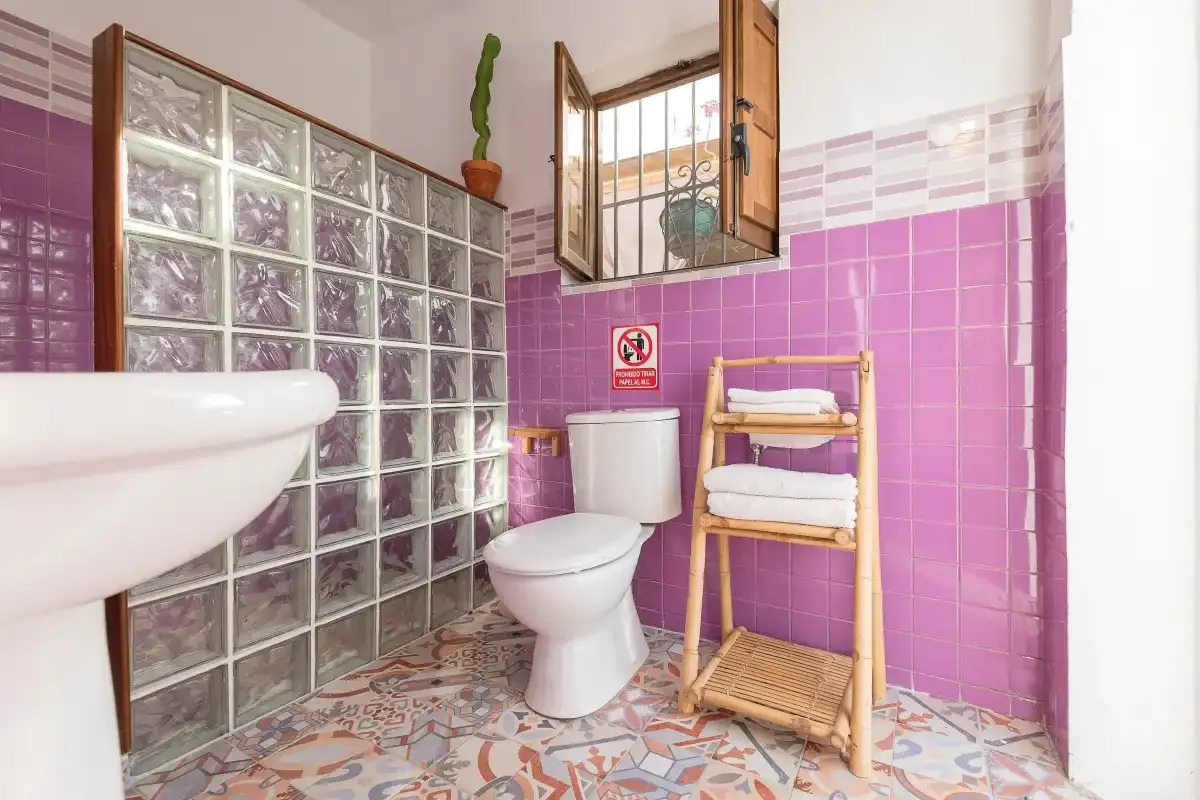 A tiled bathroom with a toilet, sink, and a small towel rack.
