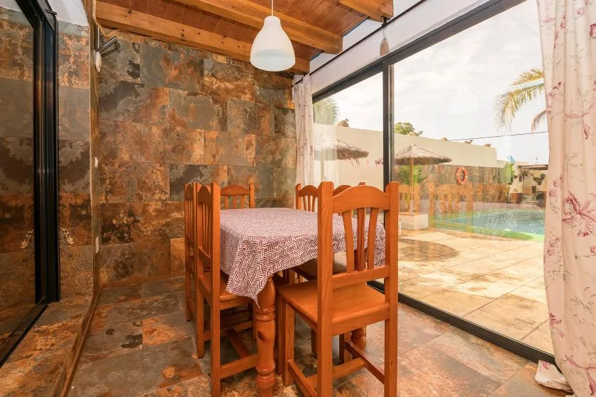 A dining area with a wooden table and chairs beside large glass doors.