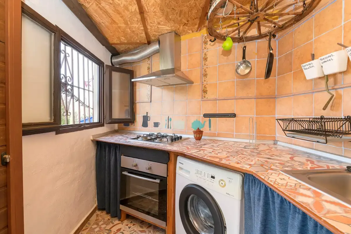 A tiled kitchen with a countertop, stovetop, oven, and washing machine.