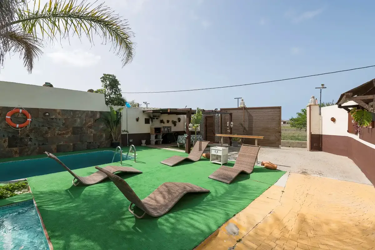 An outdoor pool area with in-water loungers and a wooden privacy screen.