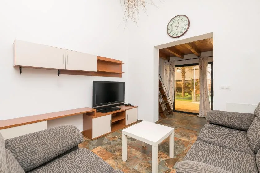 A living room with seating, a television, and a white coffee table.