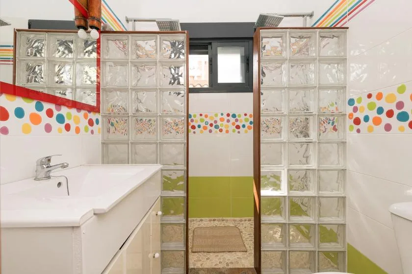 A bathroom with glass-block partitions, a sink, and colorful polka-dot wall trim.