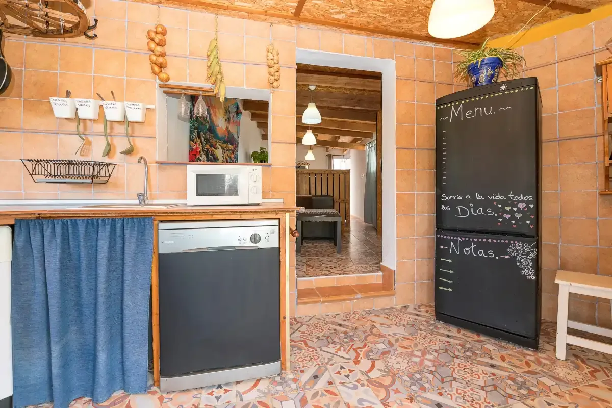 A tiled kitchen with a counter, sink, and dark chalkboard menu.