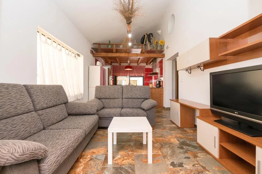 A living room with gray seating, a white coffee table, and a television.