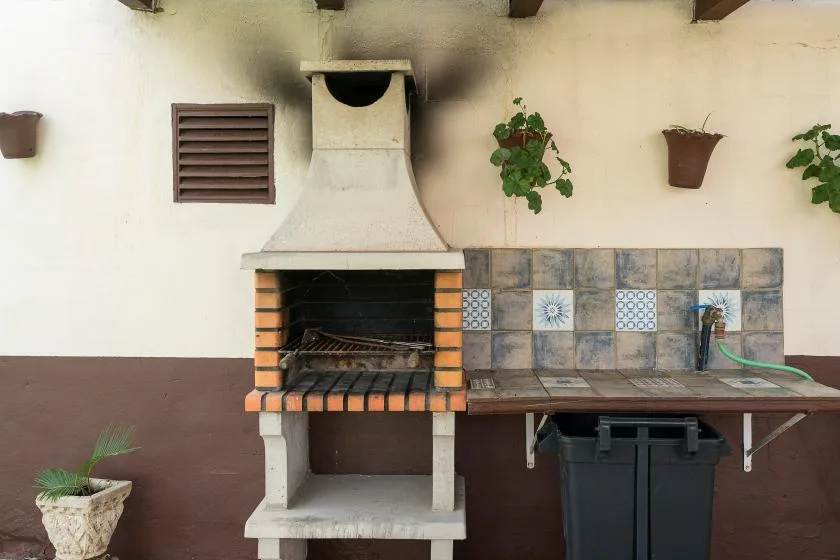An outdoor barbecue area with a tiled counter and wall-mounted planters.
