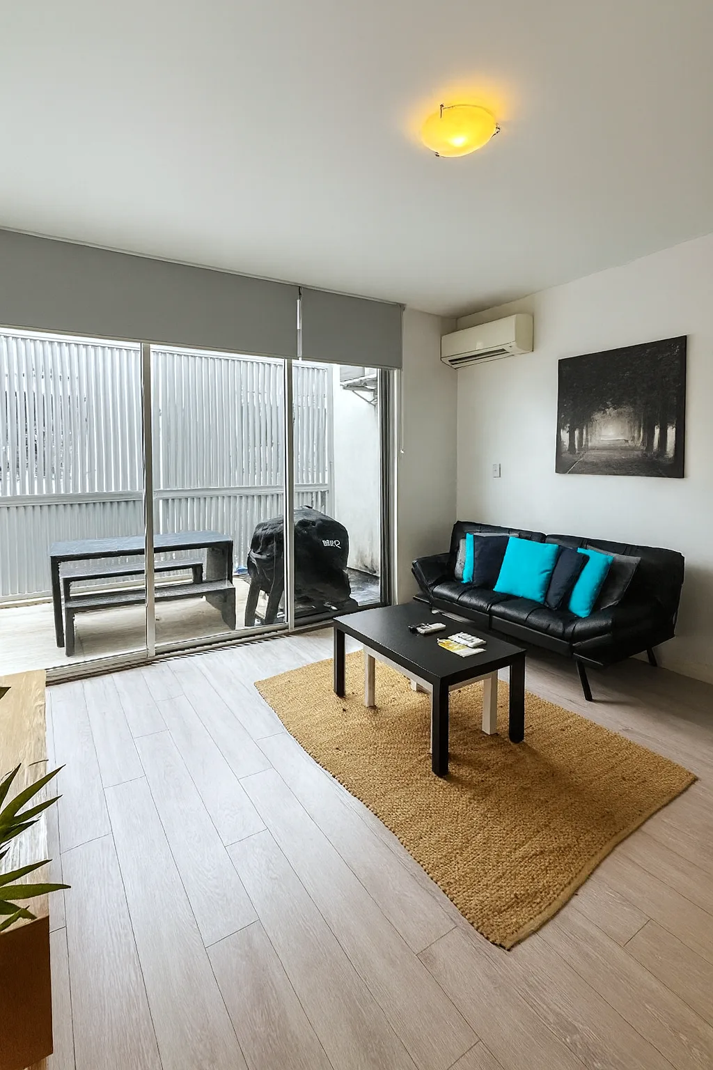 Una sala de estar con asientos negros y una mesa de centro da a puertas corredizas de vidrio.