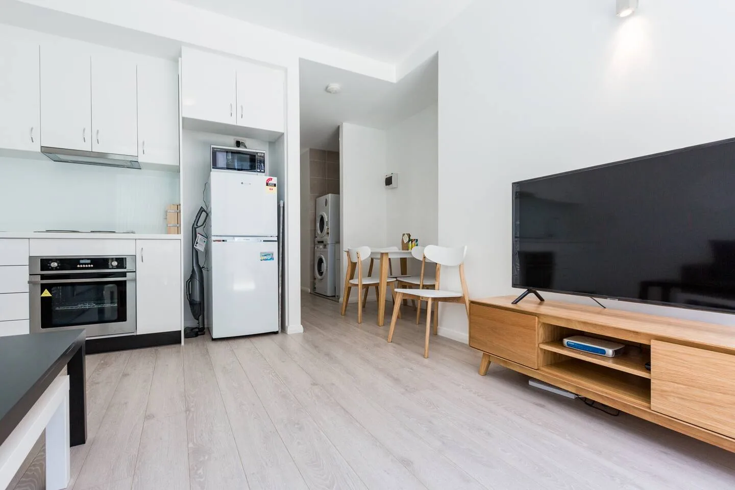 An open-plan living and kitchen area has a dining table and television.