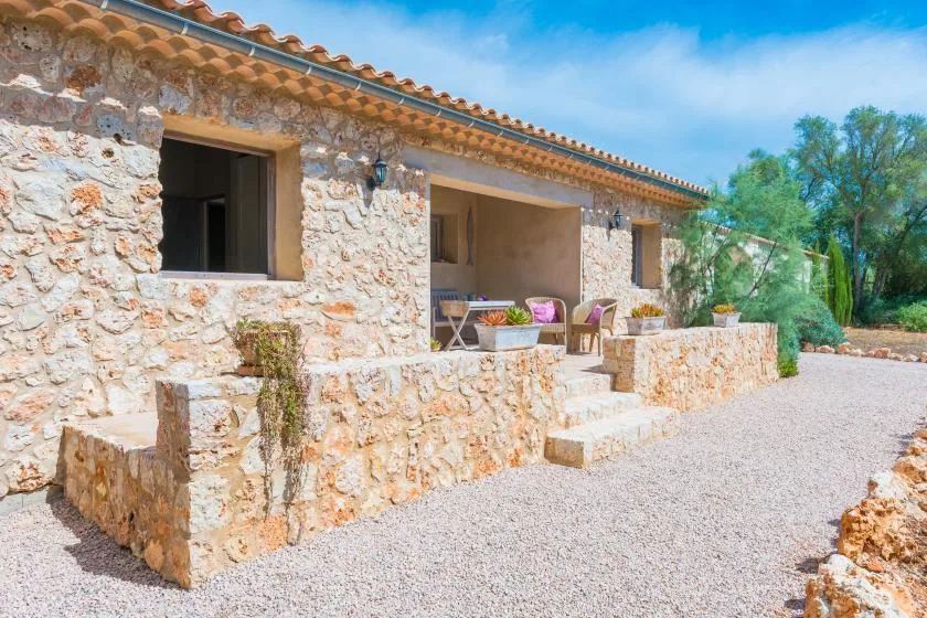 Un edificio de piedra con un patio de grava y asientos al aire libre.