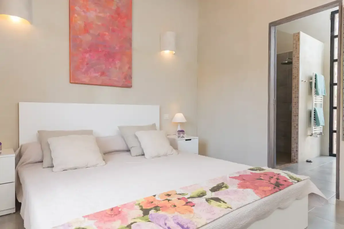 Dormitorio con una cama grande y ropa de cama floral colorida.