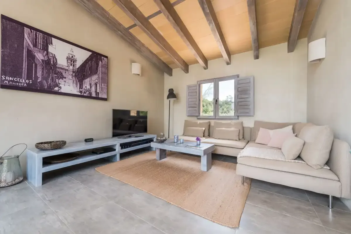 Sala de estar con zona de asientos, mesa de centro y televisor.