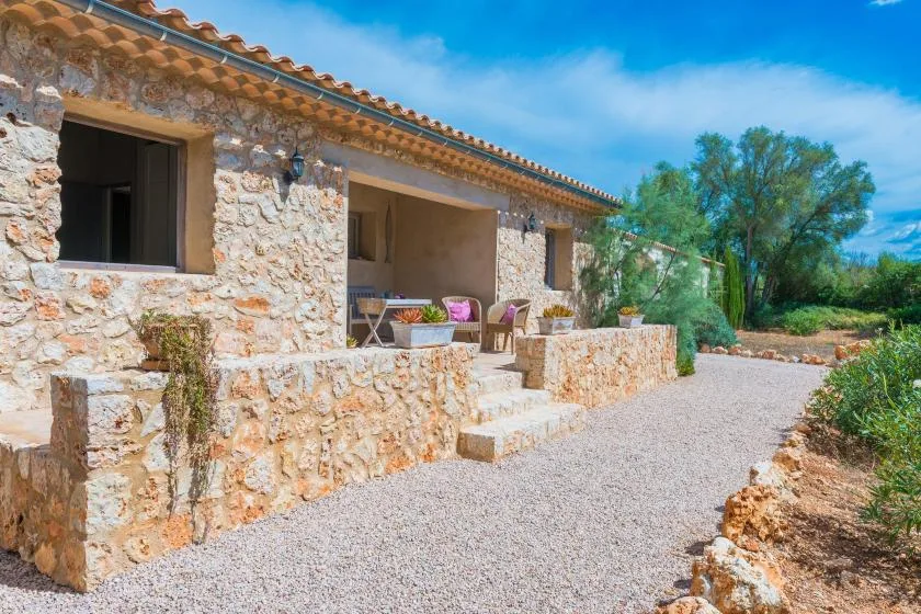 Un edificio de piedra se abre a un patio de grava con asientos al aire libre.