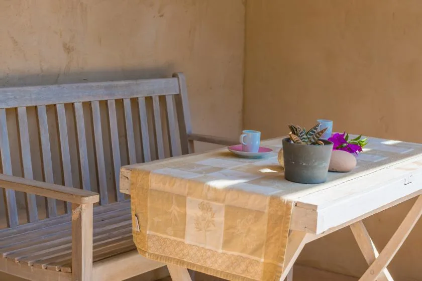 Una pequeña zona de estar al aire libre con un banco de madera y una mesa con plantas en macetas.