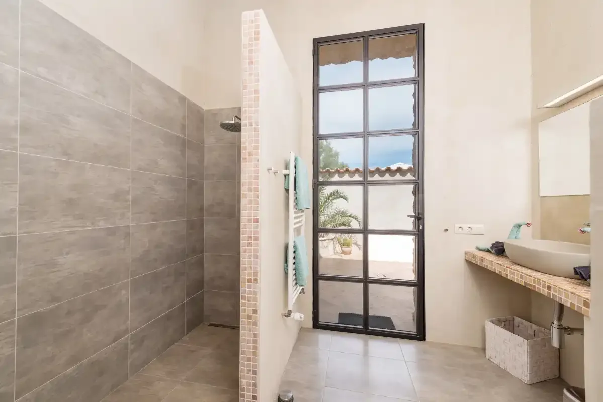 Un baño alicatado con ducha, lavabo y ventana.