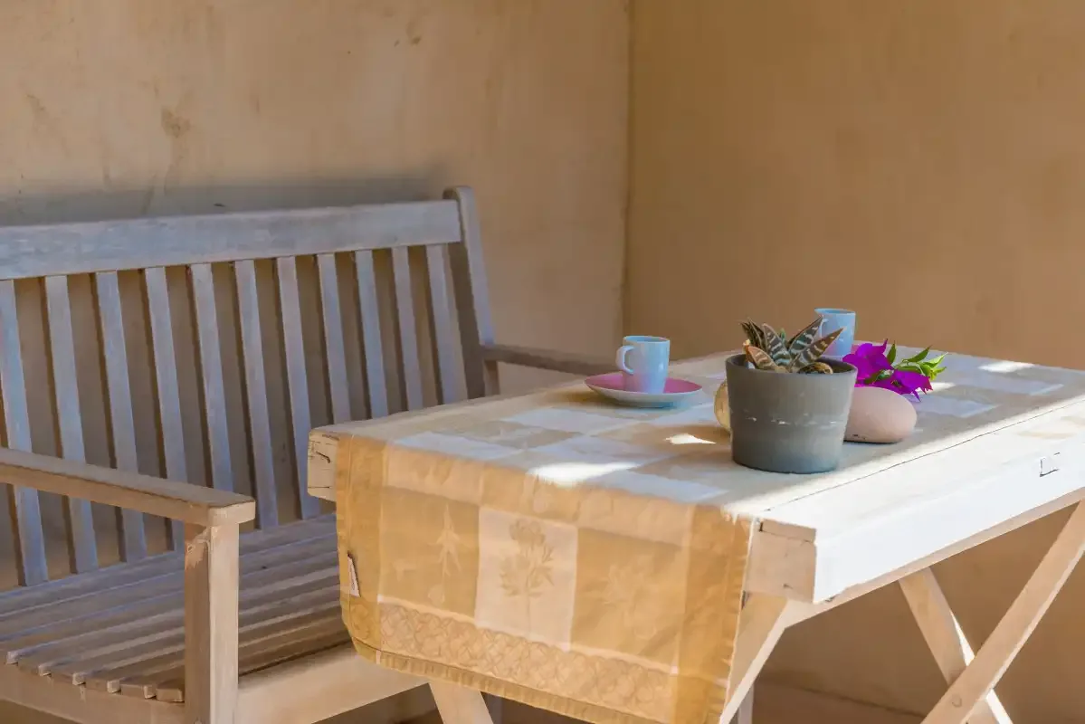 Una pequeña zona de estar en el patio, con un banco de madera junto a una mesa.