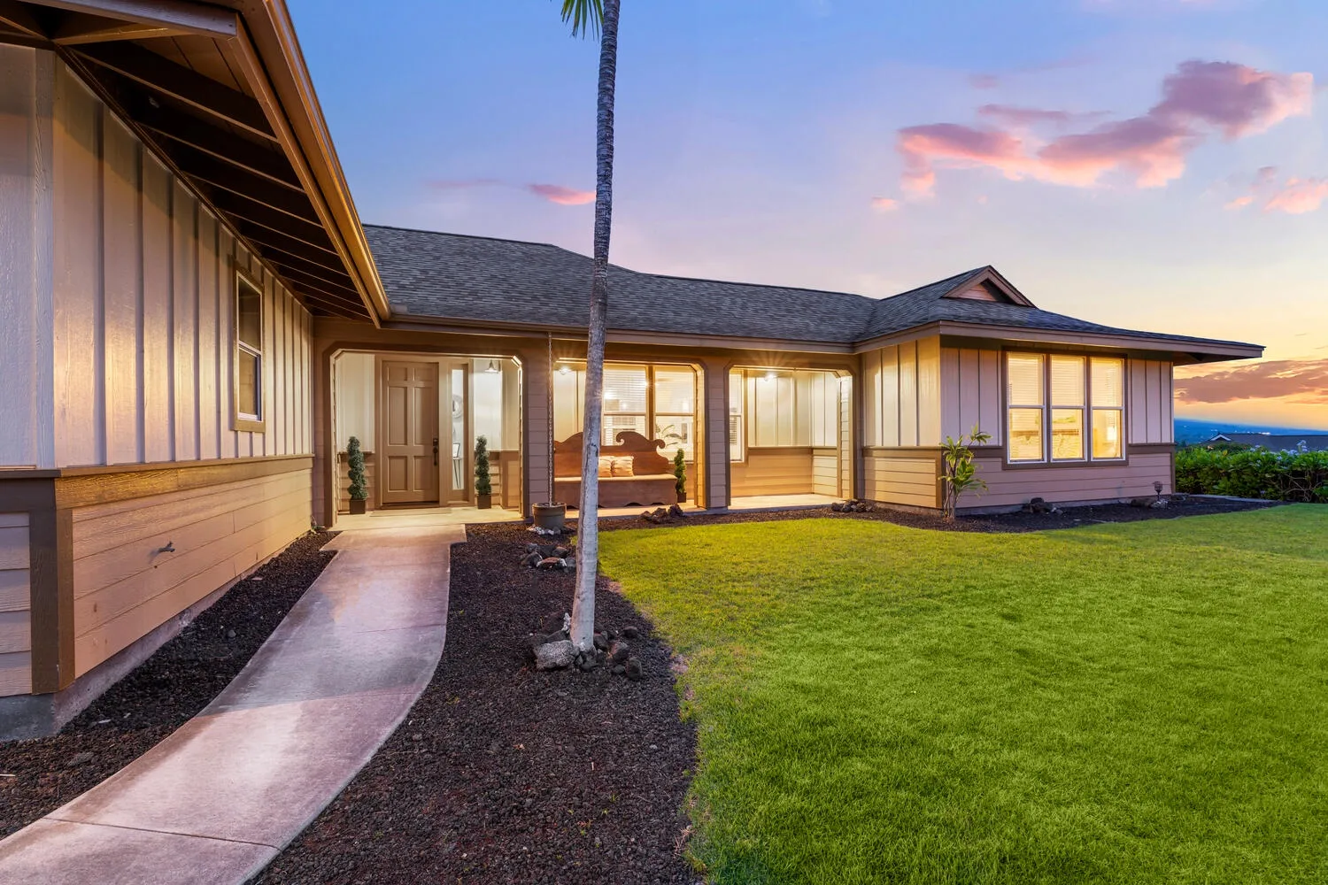 A single-story house with a curved walkway and lawn at dusk.