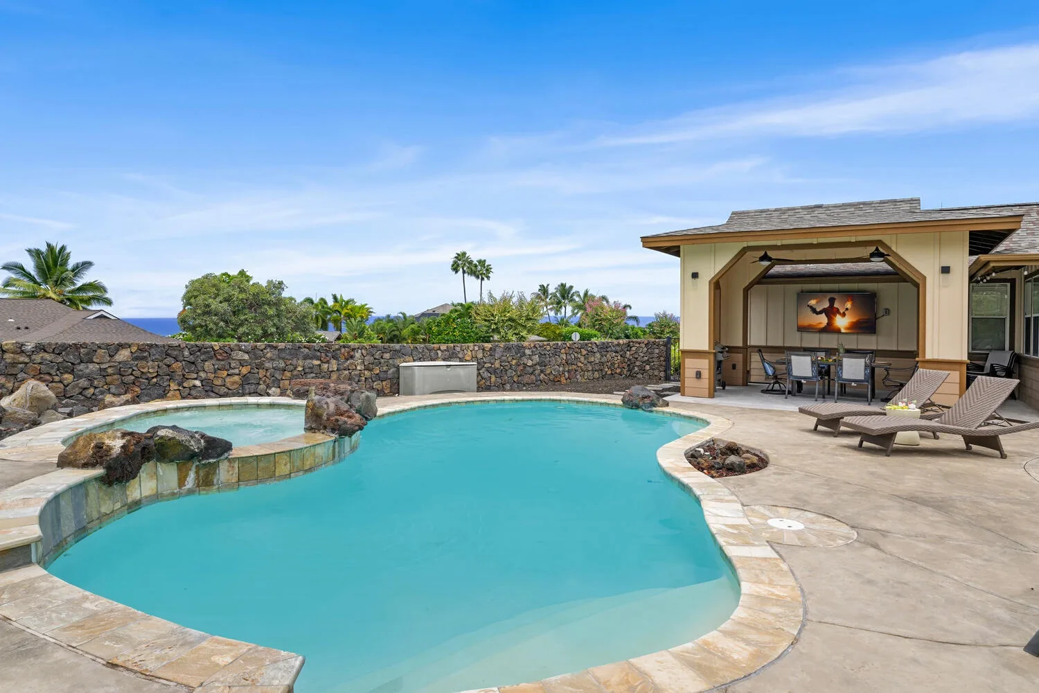 An outdoor swimming pool beside a covered patio with seating.