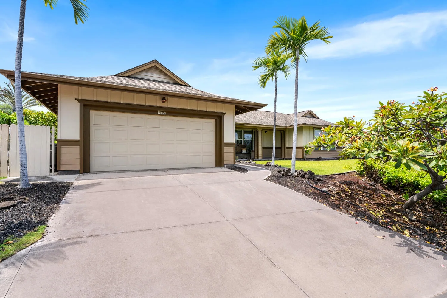 A house with a garage opens onto a broad paved driveway.
