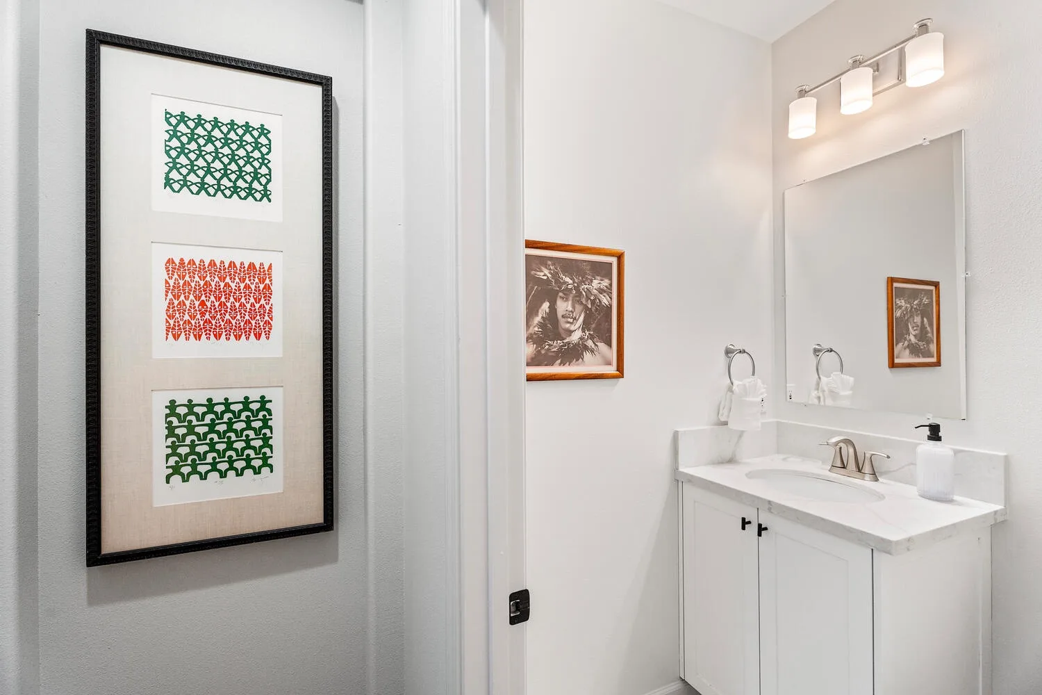 A bright bathroom vanity with a large mirror and framed artwork.