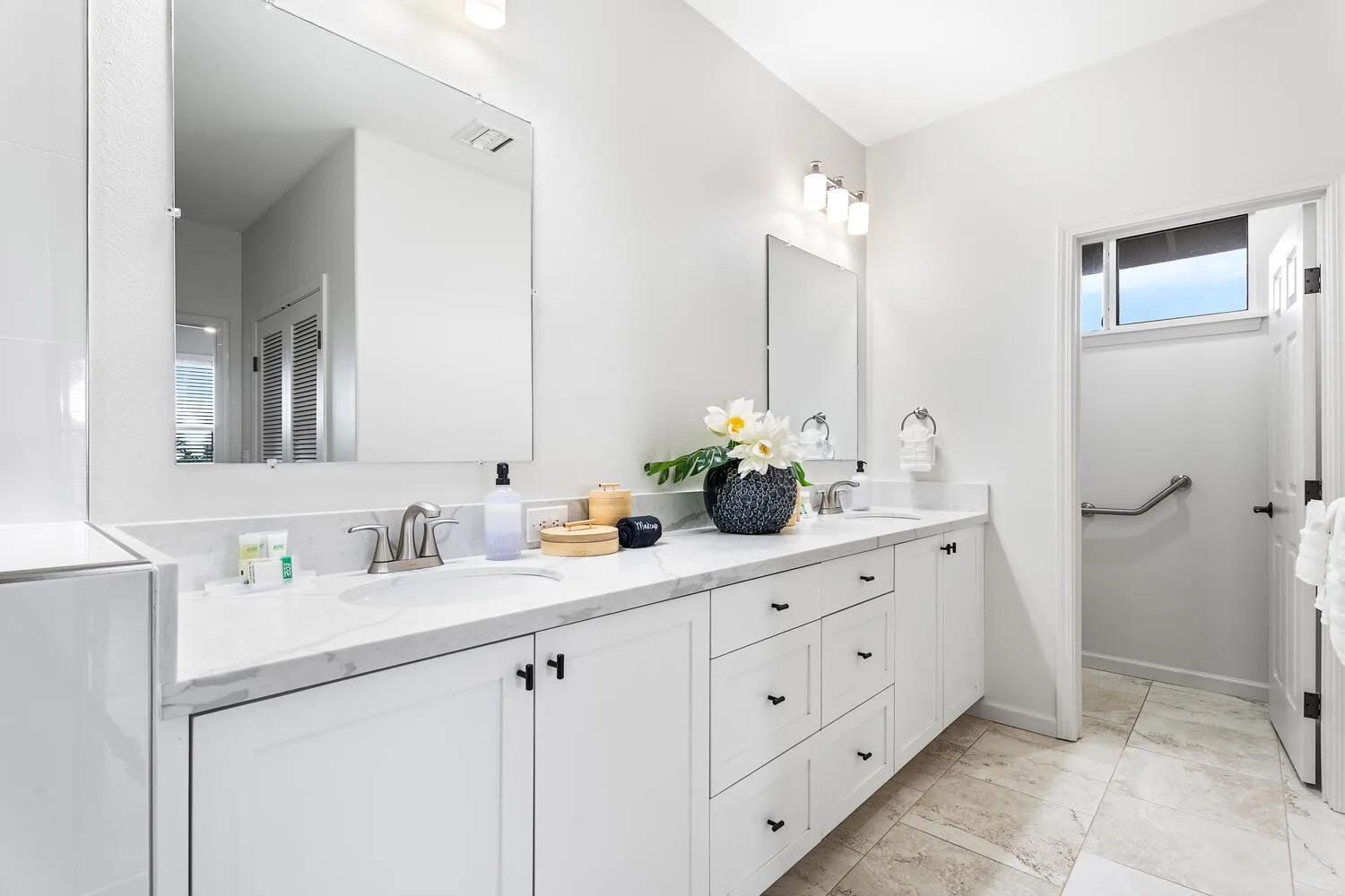 A bright bathroom with a long vanity, mirrors, and a walk-in shower.