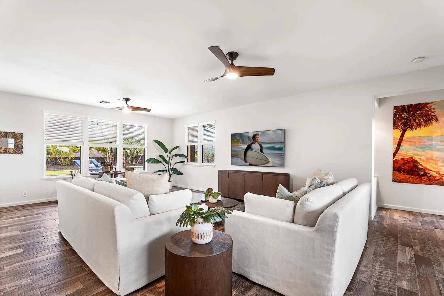 A bright living room with white seating, large windows, and a wooden coffee table.