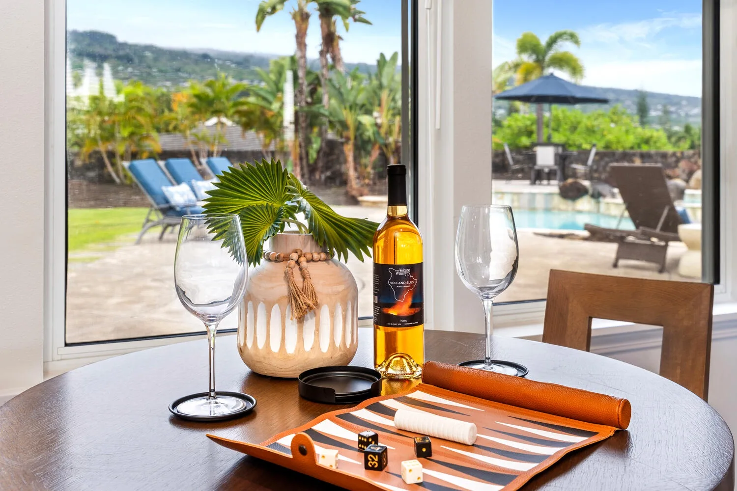 A table by a large window overlooks a sunny poolside patio.