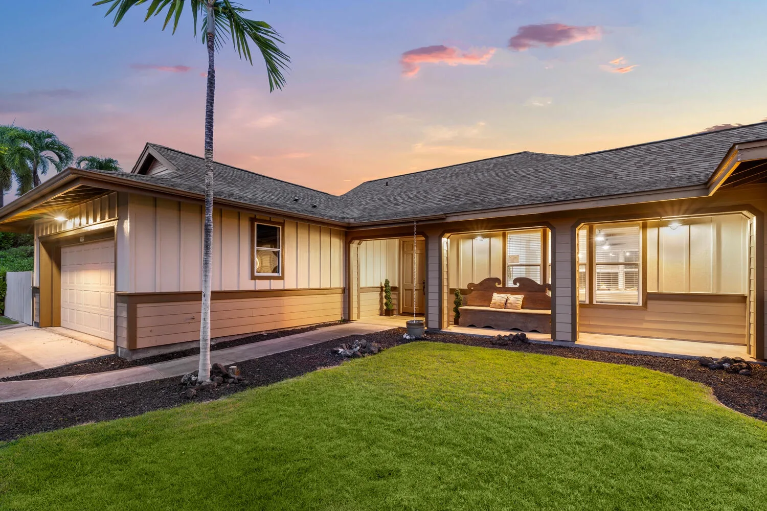 A single-story house with a lawn and palm tree at sunset.
