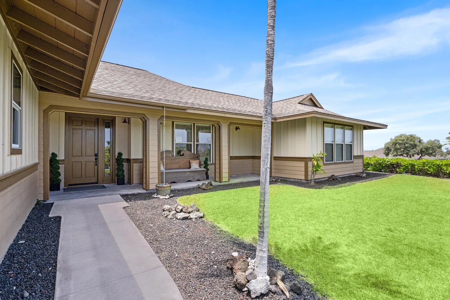 A single-story house with a covered entry and a green lawn.