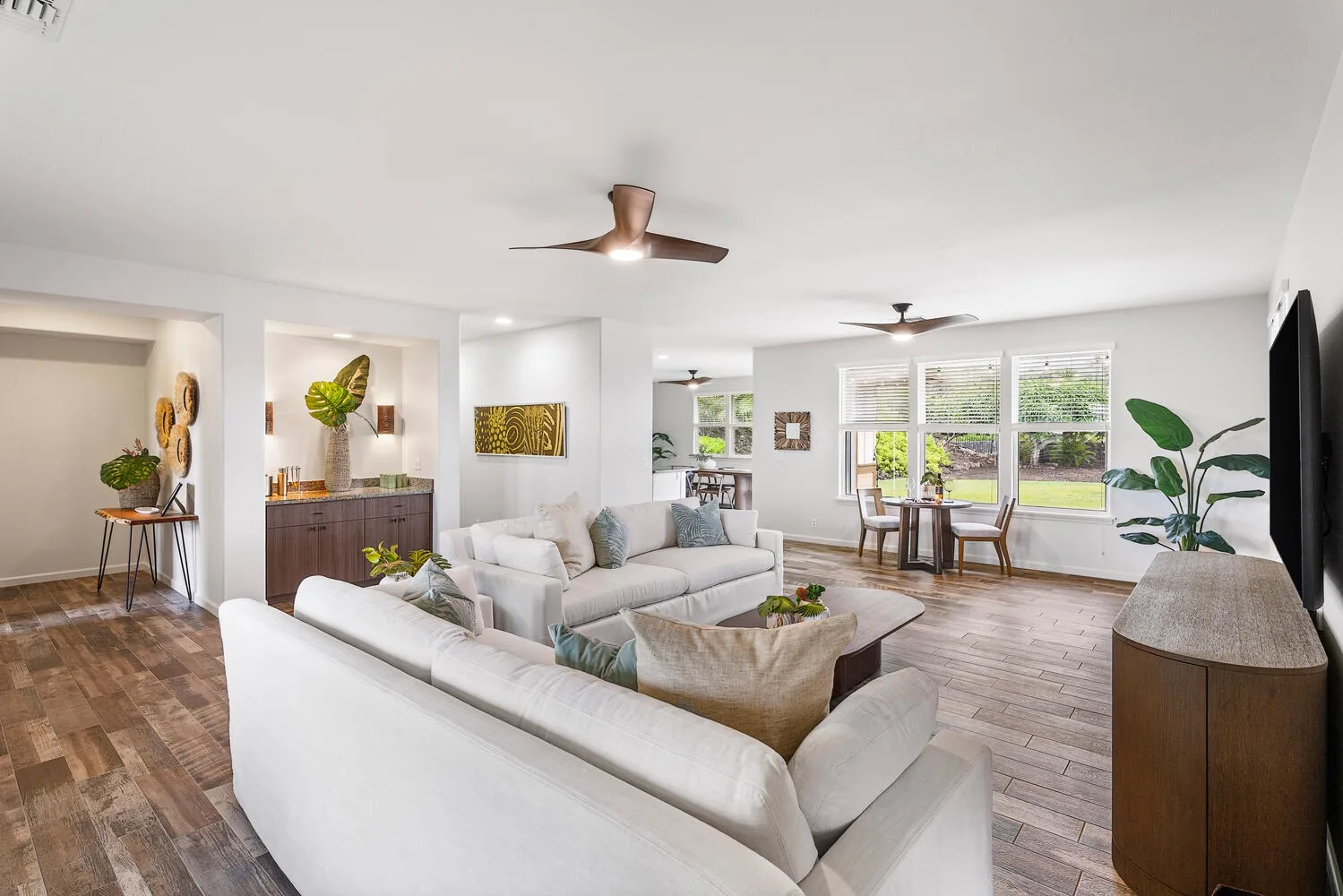 Living room with light-colored seating, a coffee table, and large windows.