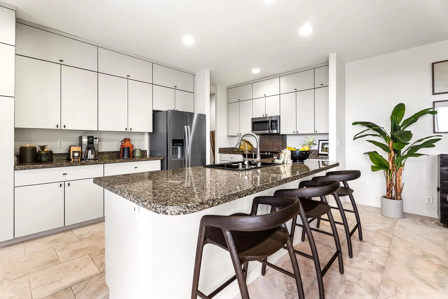 A bright kitchen with white cabinets and a large island with seating.