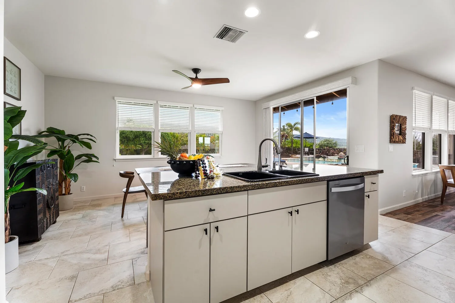A bright kitchen with a central island and windows overlooking a patio.