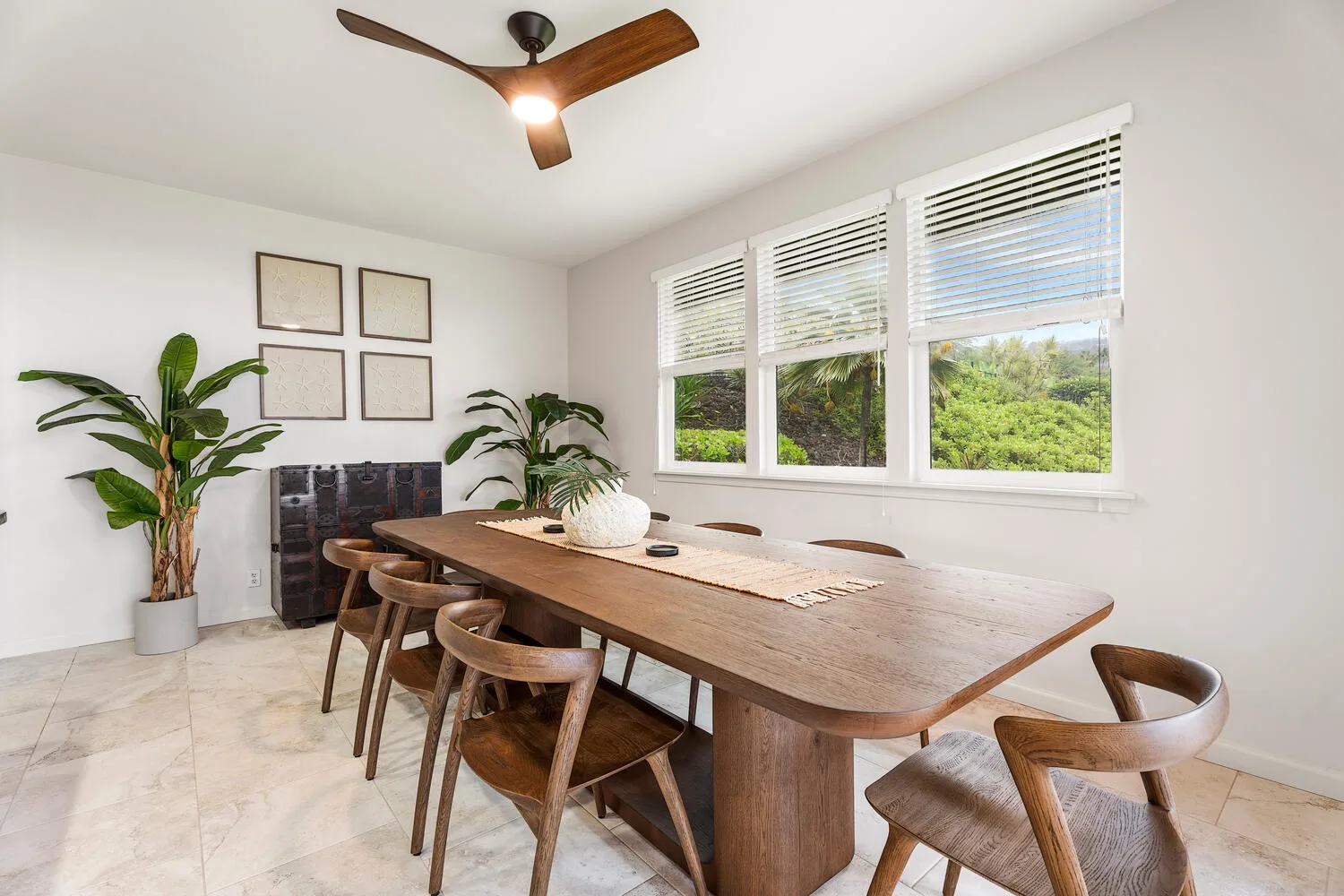 A bright dining room with a wooden table, chairs, and wide windows.