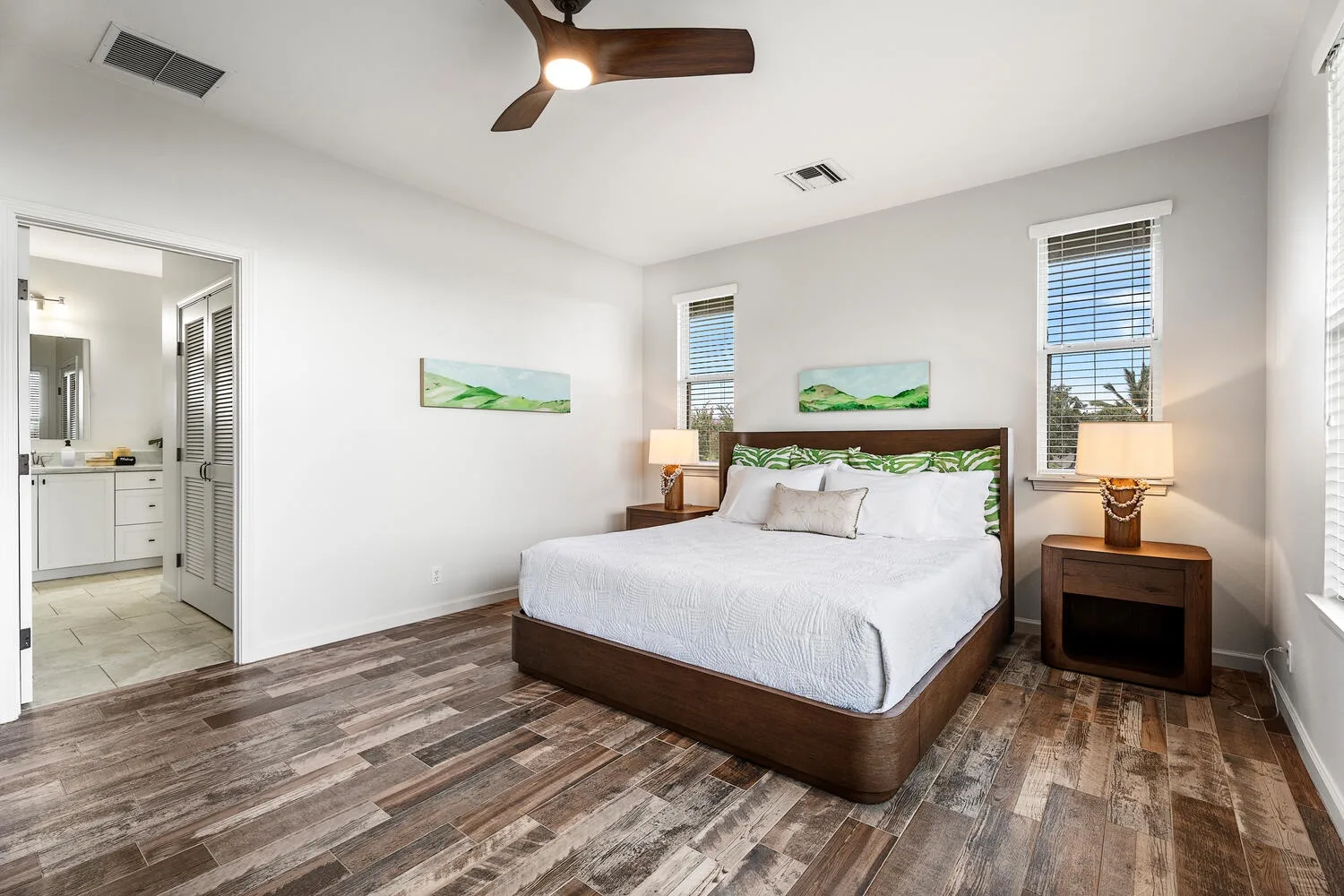 A bedroom with a large bed, bedside tables, and windows.