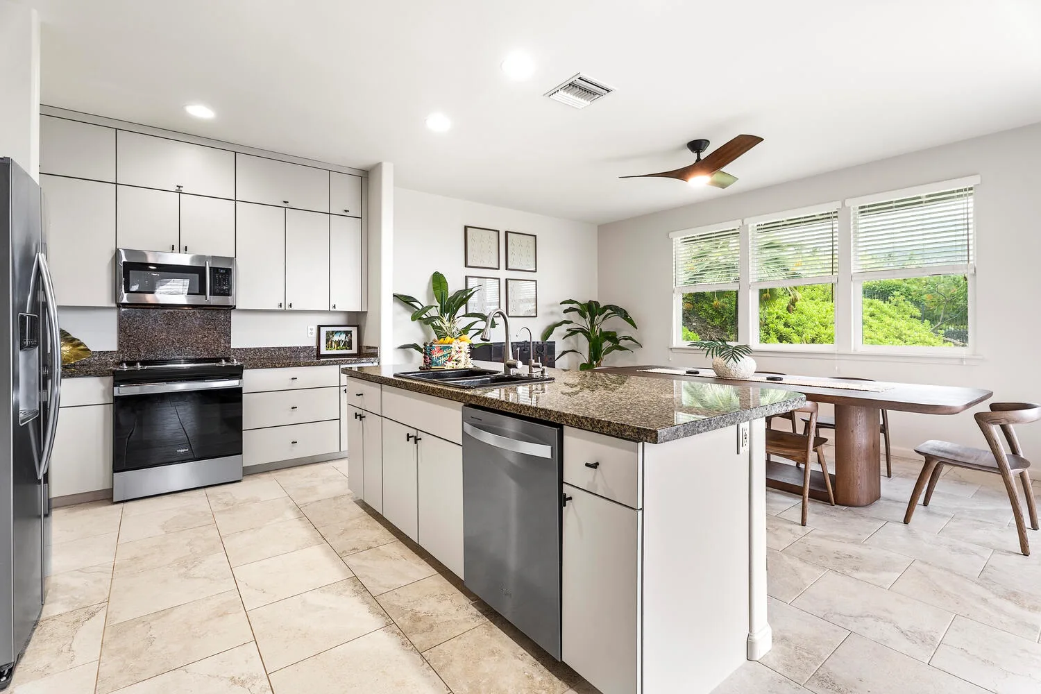 A bright kitchen with a central island and windows overlooking greenery.