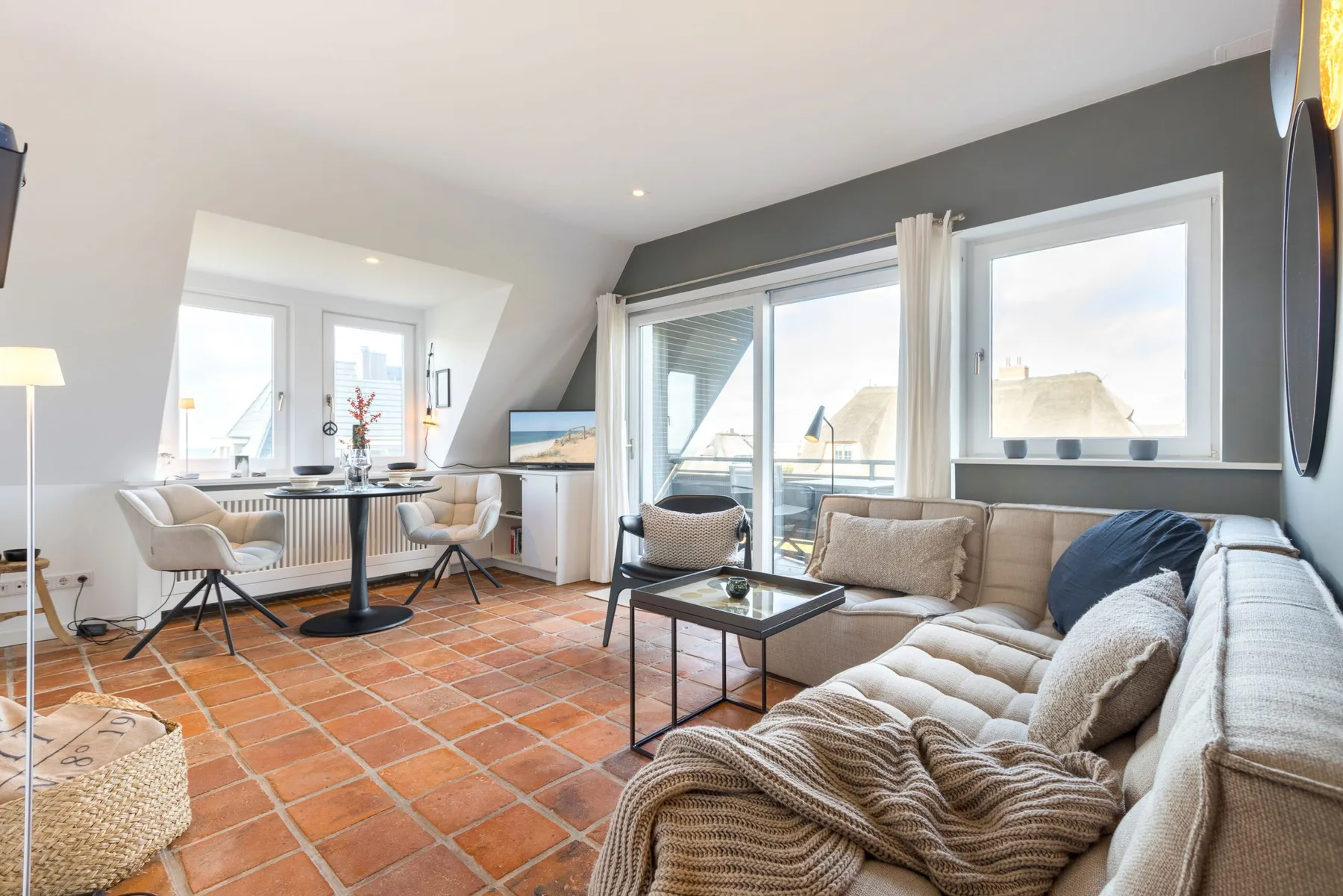 A bright living room with a dining table, seating, and large windows.