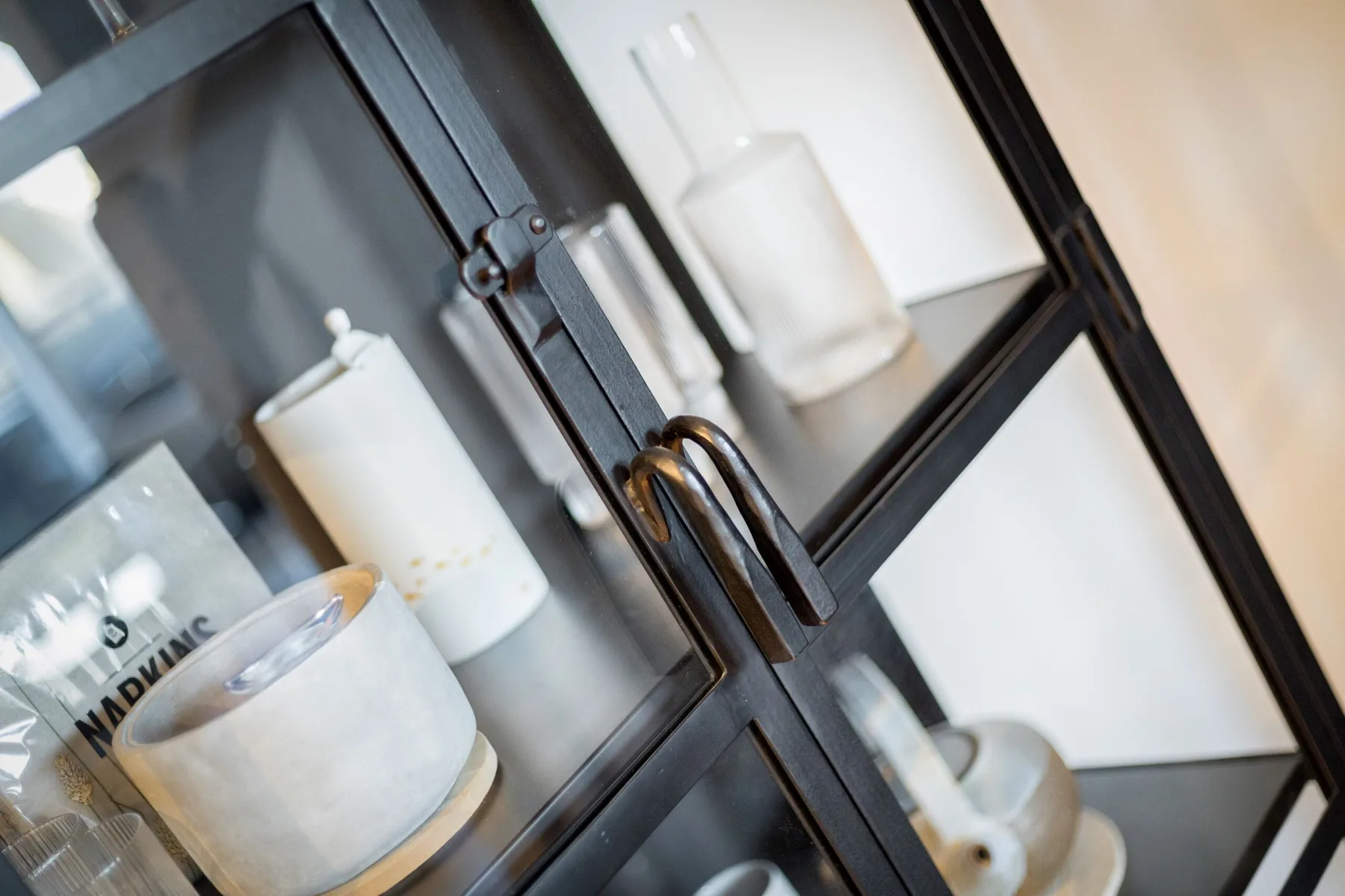 A glass-fronted cabinet displays white ceramic containers and small decorative objects.