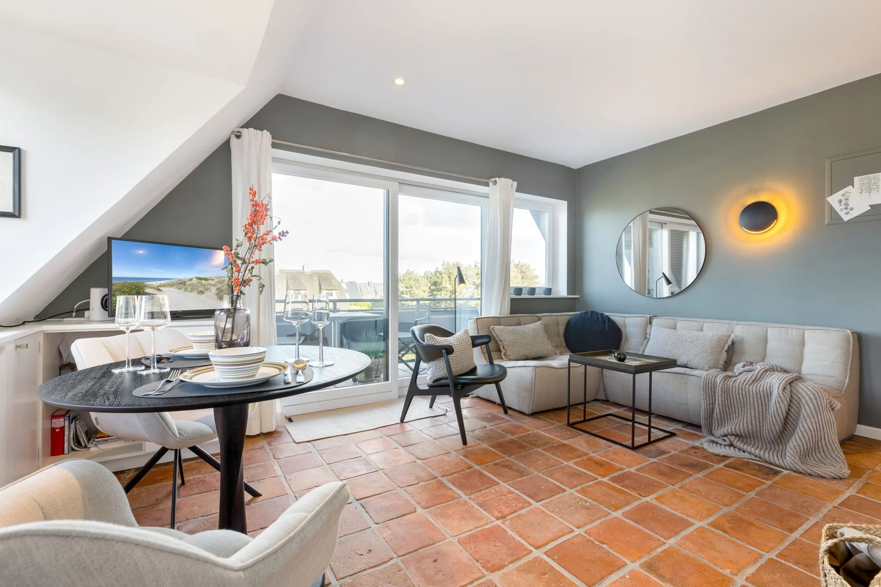 A bright living and dining area with a sectional seating area beside large windows.