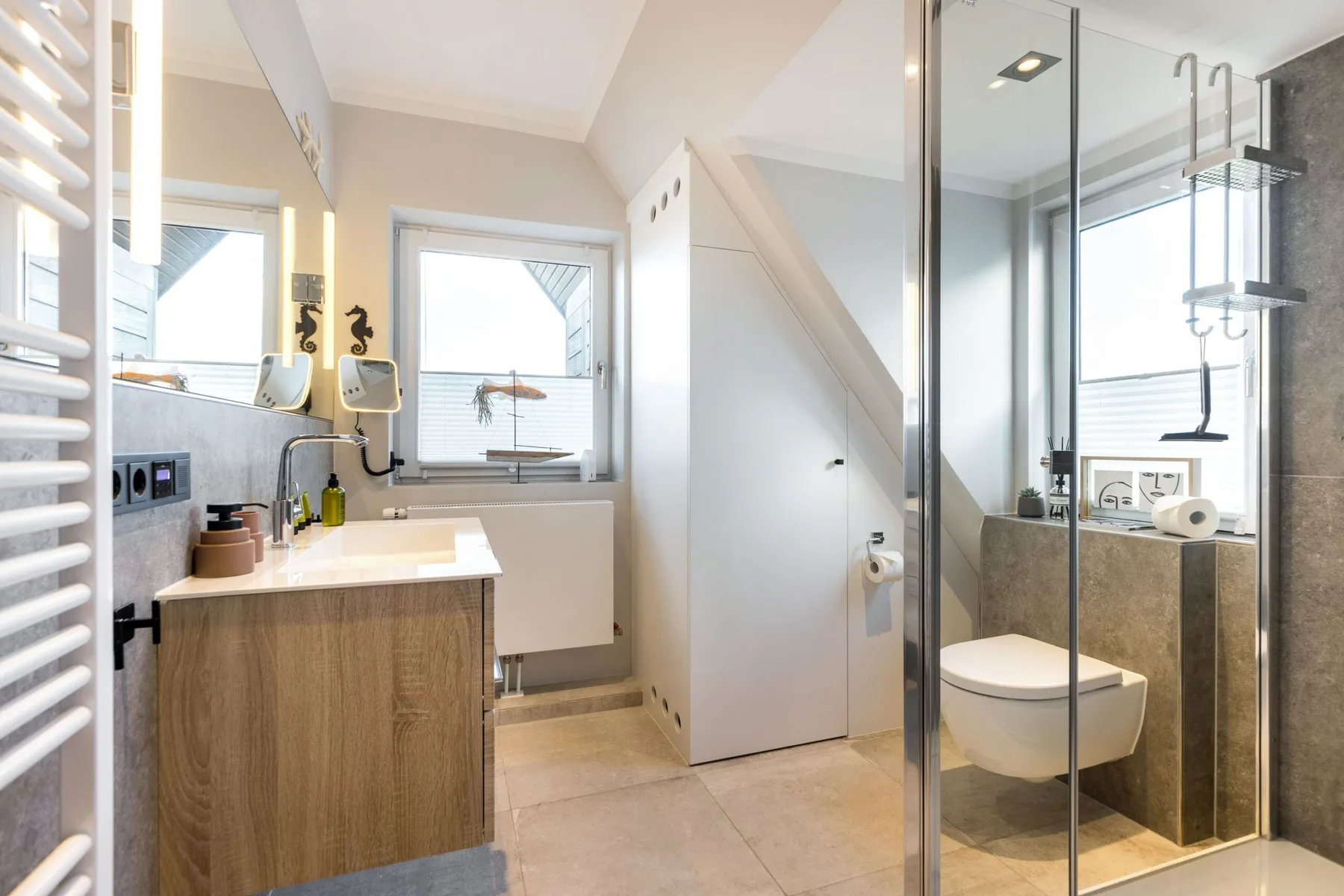 A bright bathroom with a vanity, toilet, and glass-enclosed shower.