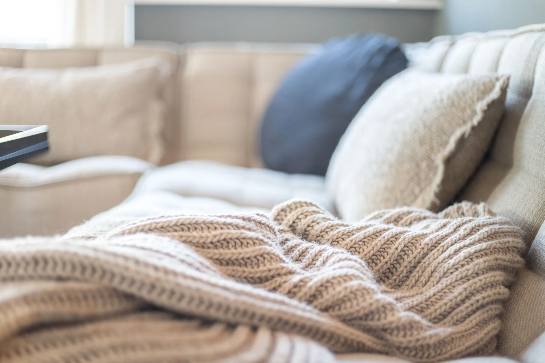 A cozy living room seating area with a knitted throw draped over the sofa.