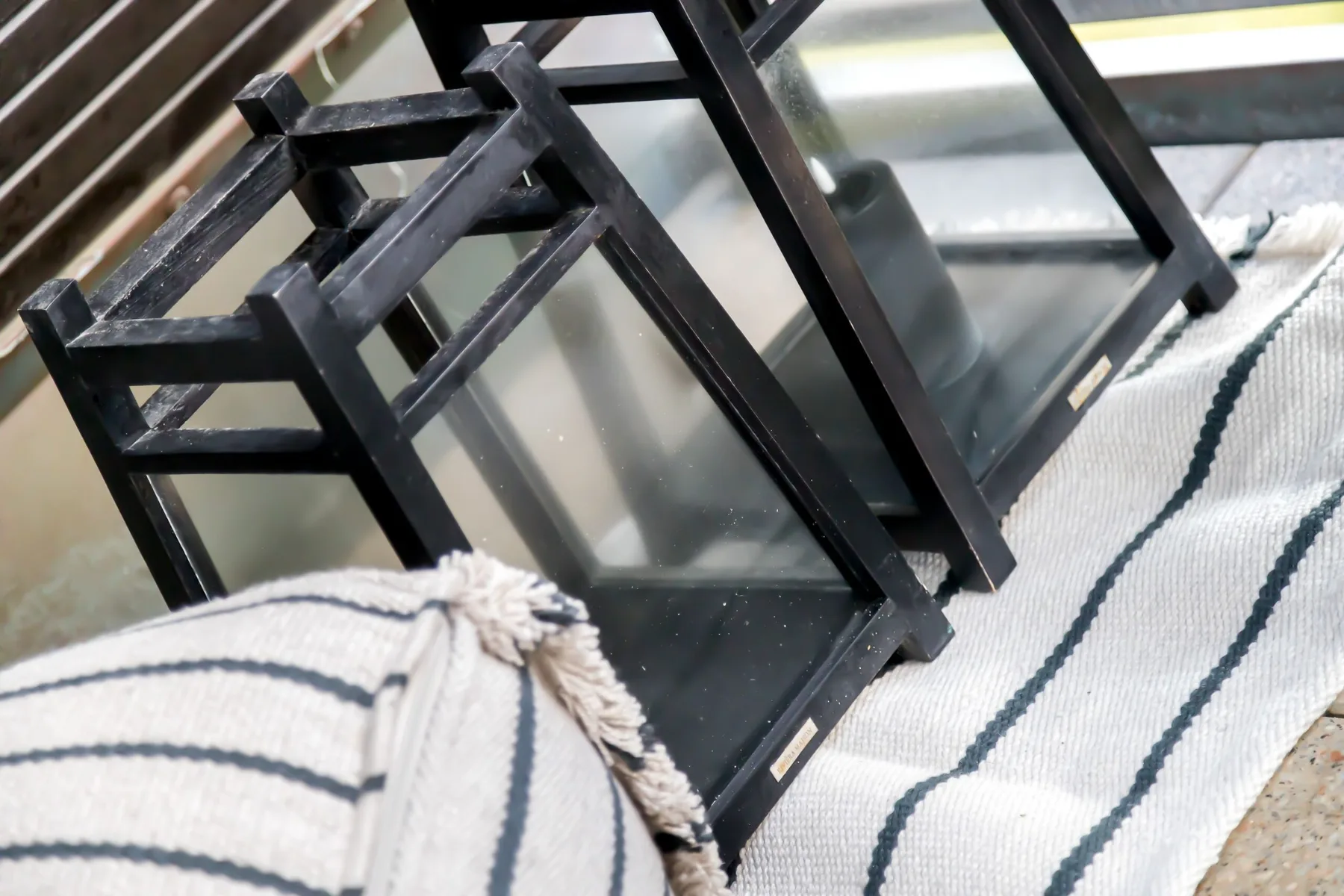 Close-up of black-framed glass furniture on a striped rug.