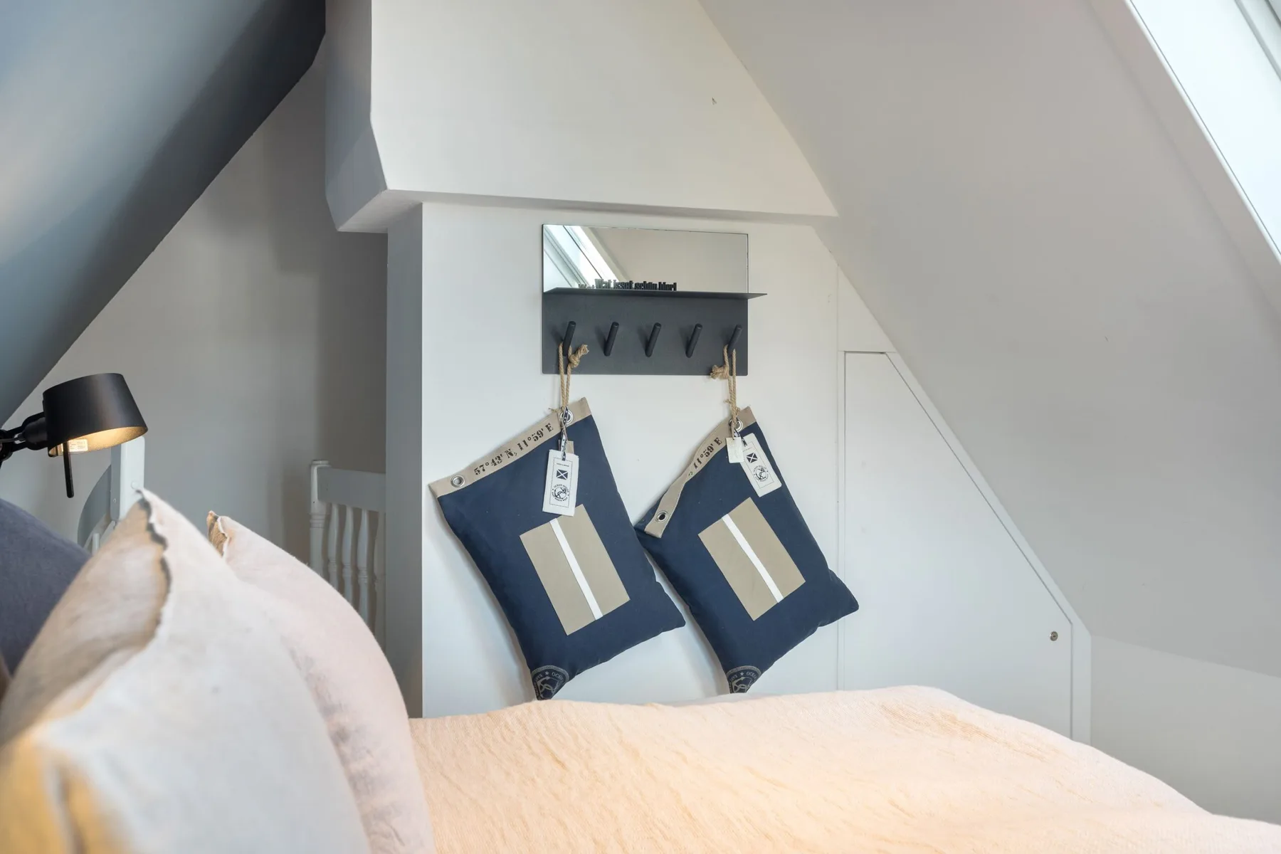 Bedroom with a bed beneath a sloped ceiling and two hanging bags.