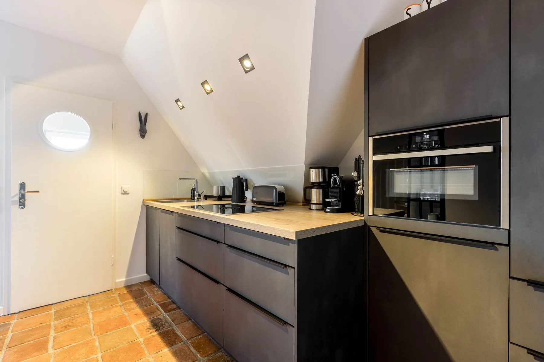 A compact kitchen with dark cabinets, a countertop, and built-in appliances.