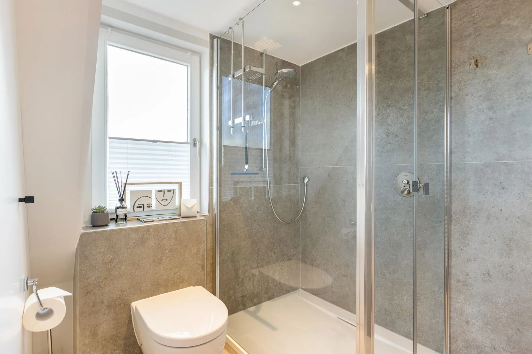A bathroom with a glass-enclosed shower and a toilet beside the window.
