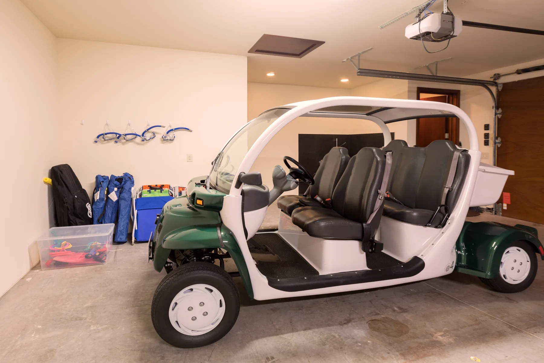 Un carrito de golf verde y blanco está estacionado en un garaje, junto a objetos guardados.