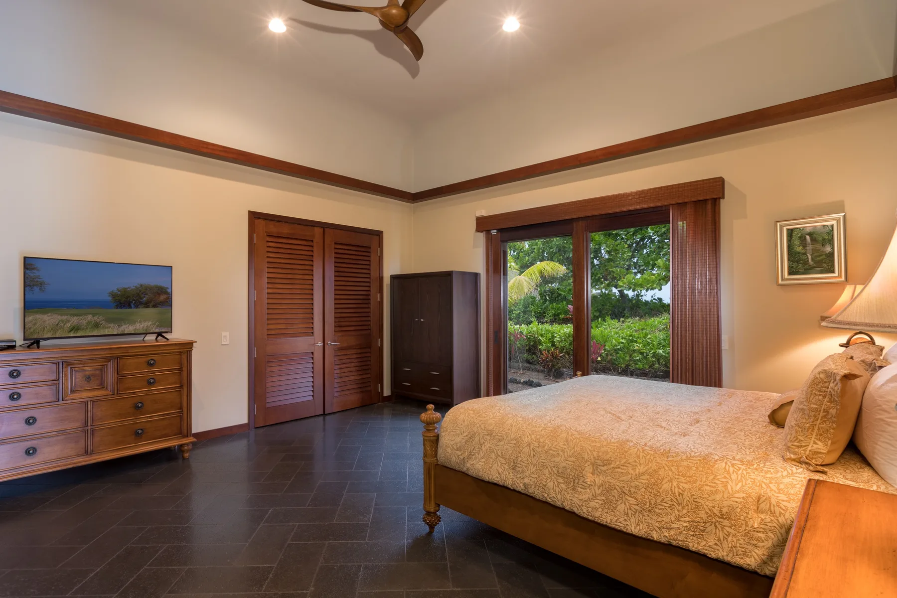 Un dormitorio con una cama, puertas de armario de madera y vista al jardín por la ventana.