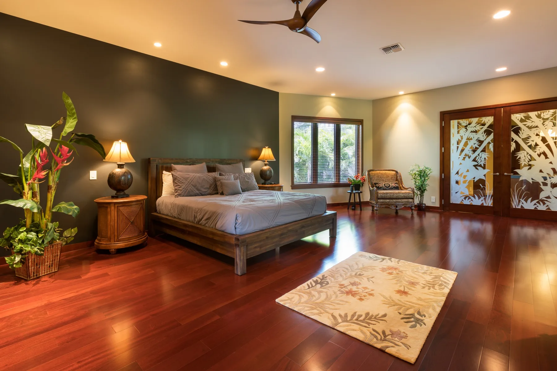 Un dormitorio con una cama grande, piso de madera oscura y puertas corredizas decorativas.