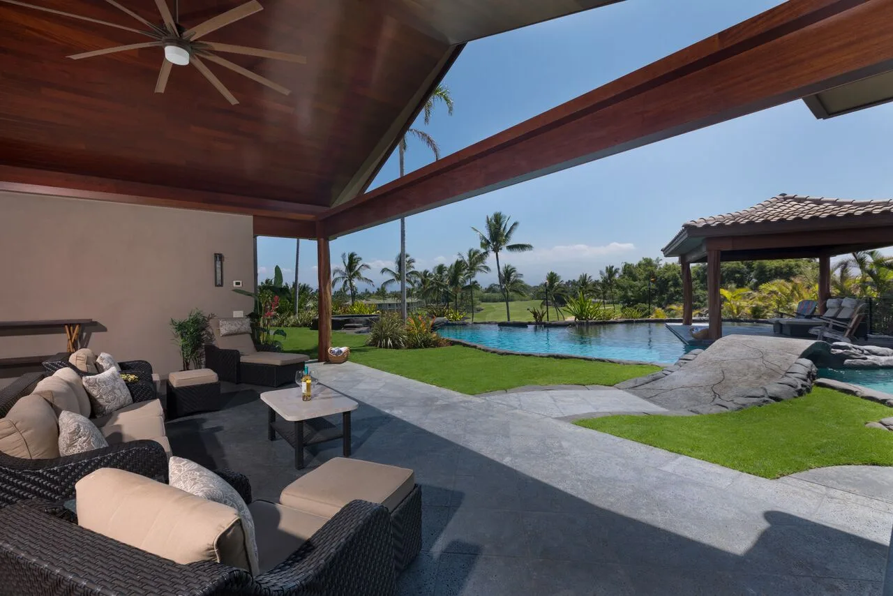 Una sala exterior cubierta da a una piscina y a jardines.