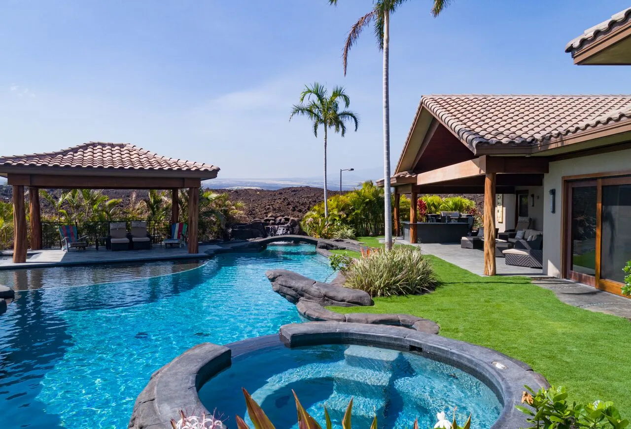 Una zona de piscina ajardinada con una piscina circular pequeña junto a un patio cubierto.