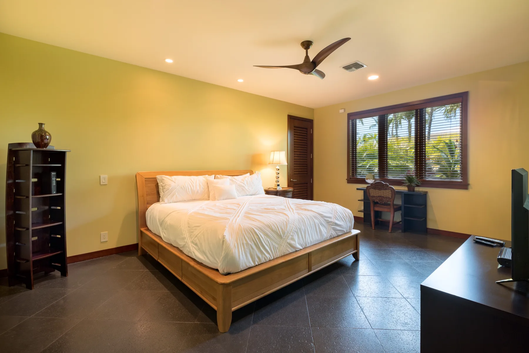 Un dormitorio con una cama grande y una ventana con vista a la vegetación.